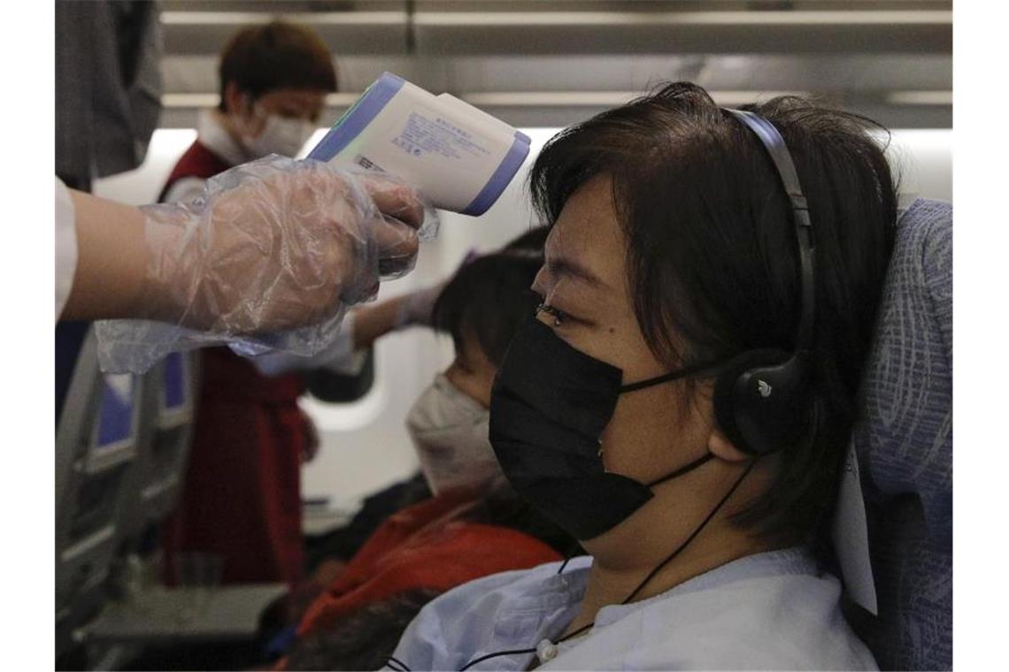 Flugbegleiter messen zur Vorsicht die Körpertemperaturen der Passagiere auf einem Air-China-Flug von Melbourne nach Peking. Foto: Andy Wong/AP/dpa