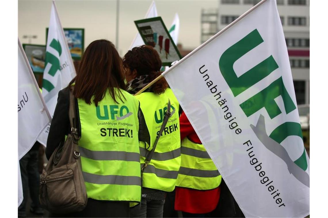 Flugbegleiter von Lufthansa-Töchtern Eurowings und Germanwings stehen mit Fahnen der Gewerkschaft UFO (Unabhängige Flugbegleiter Organisation) bei einer Kundgebung vor der Unternehmenszentrale. Foto: Oliver Berg