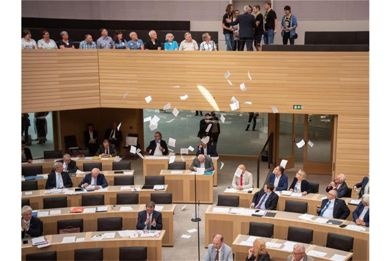Flugblätter jugendlicher Klimaschützer fliegen während von der Besuchertribüne des Landtags in den Plenarsaal. Foto: Marijan Murat/Archivbild