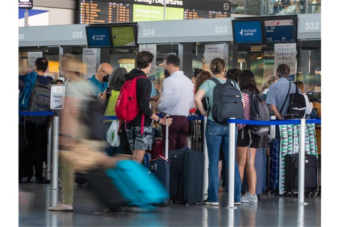 Fluggäste stehen mit ihren Koffern an einem Check-In-Schalter des Stuttgarter Flughafens. Foto: Christoph Schmidt/dpa/Archivbild