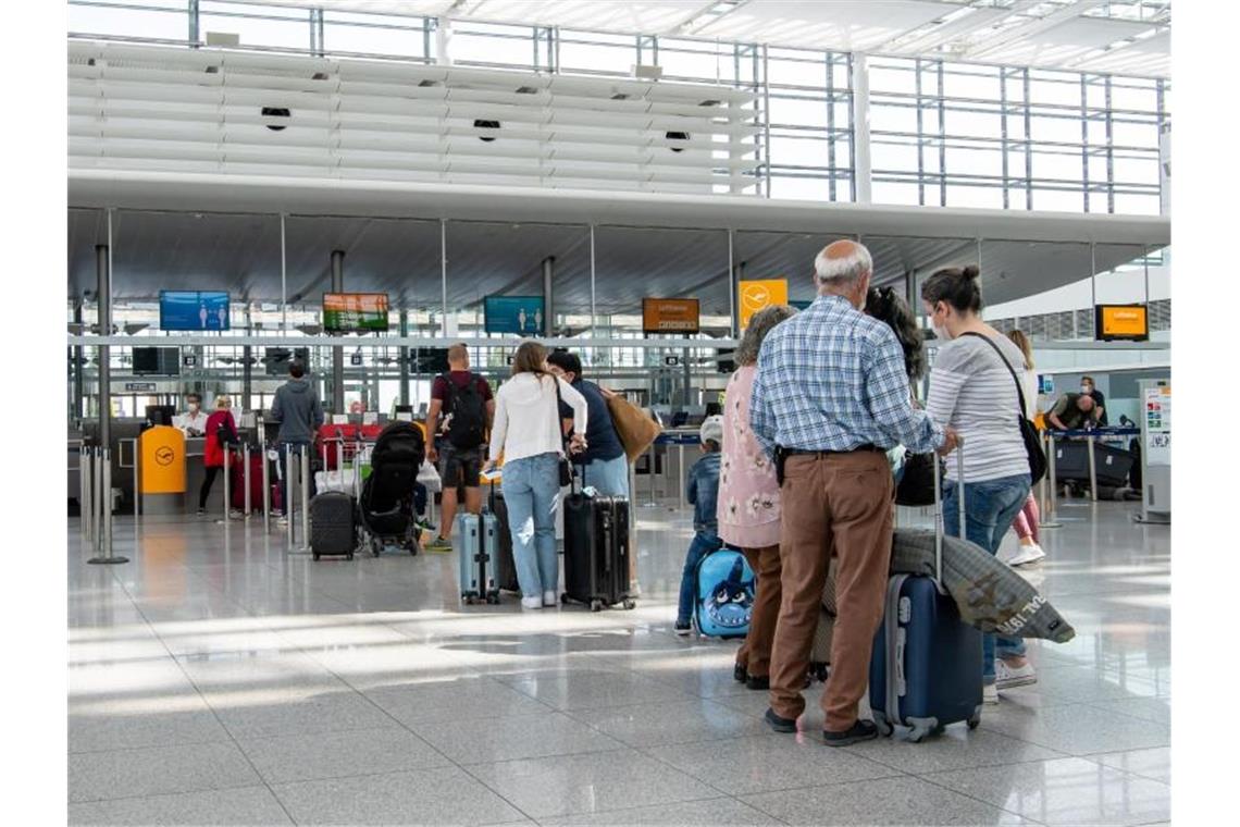 Fluggäste warten im fast leeren Terminal 2 des Münchener Flughafens auf den Check-In. Foto: Peter Kneffel/dpa