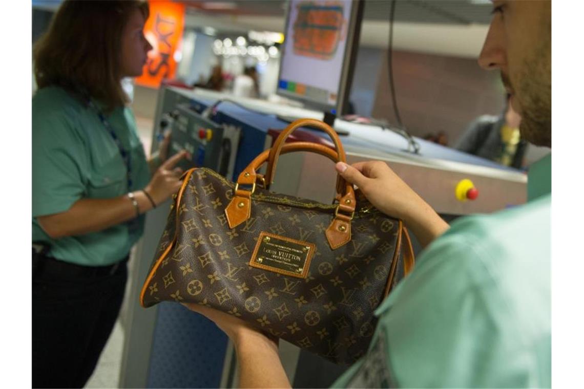 Fälschungen kosten EU-Branchen 60 Milliarden Euro pro Jahr Flughafen Düsseldorf: Ein Zollbeamter hält eine gefälschte Louis-Vuitton-Handtasche in der Hand. Foto: Matthias Balk