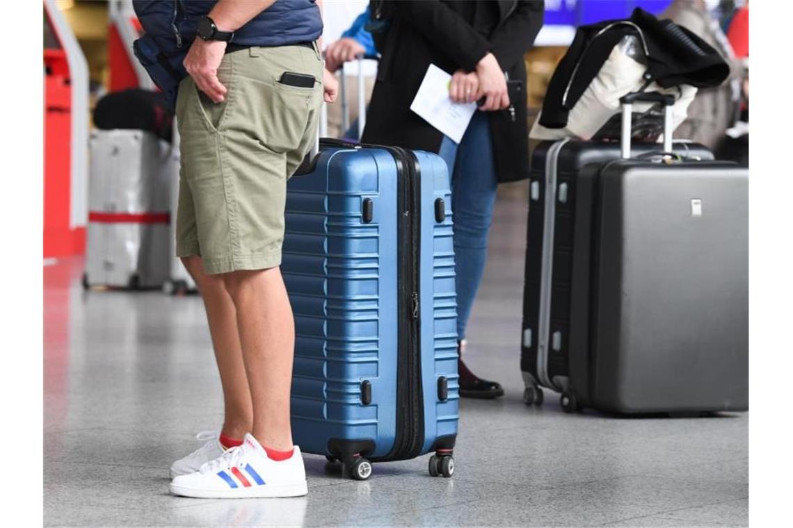 Flugreisende am Check-in-Schalter eines Flughafens. Foto: Arne Dedert/dpa