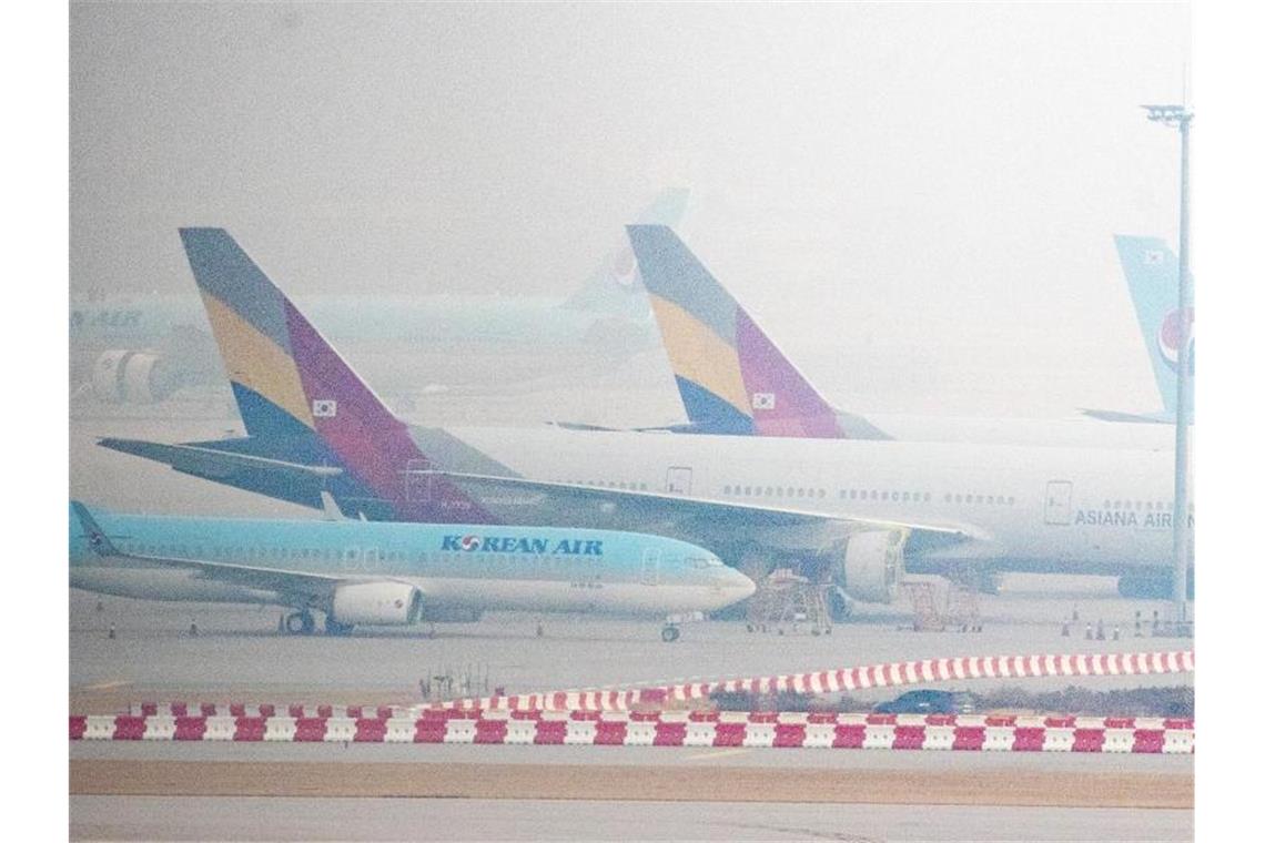 Flugzeuge der Fluggesellschaften Korean Air und Asiana Airlines stehen bei nebeligem Wetter nebeneinander am Flughafen „Incheon International Airport“ westlich von Seoul. Foto: -/YNA/dpa