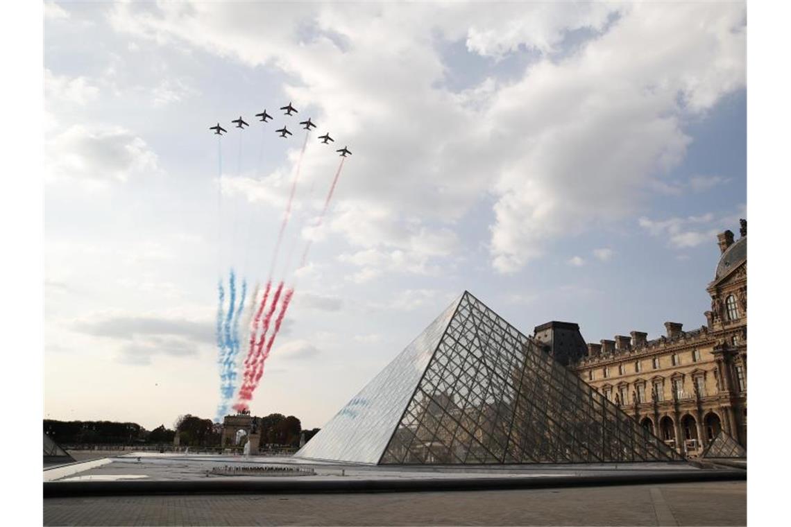 Flugzeuge der Kunstflugstaffel „Patrouille de France“ zeichnen die französische Nationalflagge über dem Museum Louvre an den Himmel. Foto: Francois Mori/AP/dpa