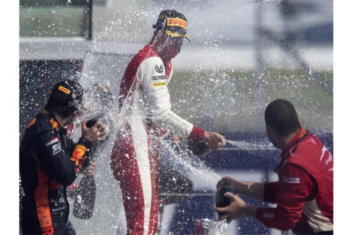 Formel-2-Pilot Mick Schumacher (M) feiert seinen Sieg in Sotschi mit Champagner. Foto: Pavel Golovkin/Pool AP/dpa