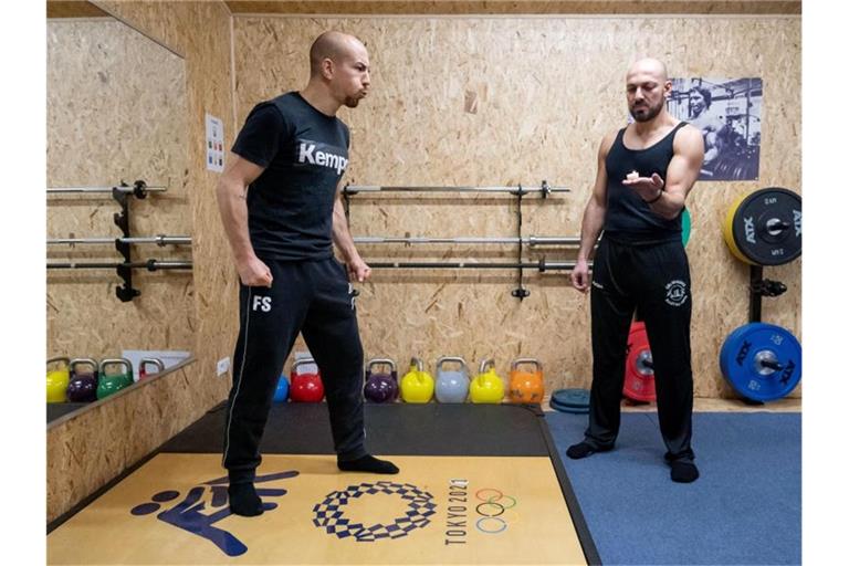 Frank Stäbler (l) bläst während eines Atemtrainings eine Kerze aus, die sein Atemtrainer Yasin Seiwasser hält. Foto: Marijan Murat/dpa