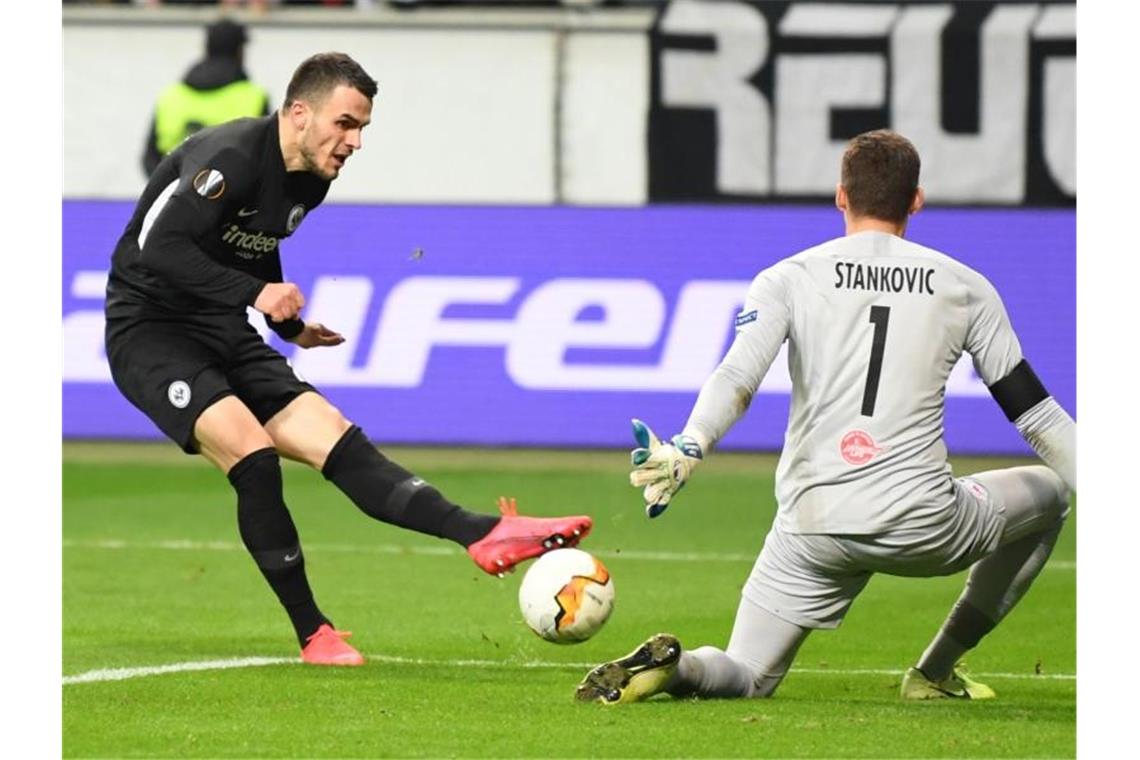 Kamada lässt die Eintracht jubeln: Achtelfinale in Sicht Frankfurts Filip Kostic (l) erzielt das Tor zum 4:0 gegen Salzburgs Torhüter Cican Stankovic. Foto: Arne Dedert/dpa