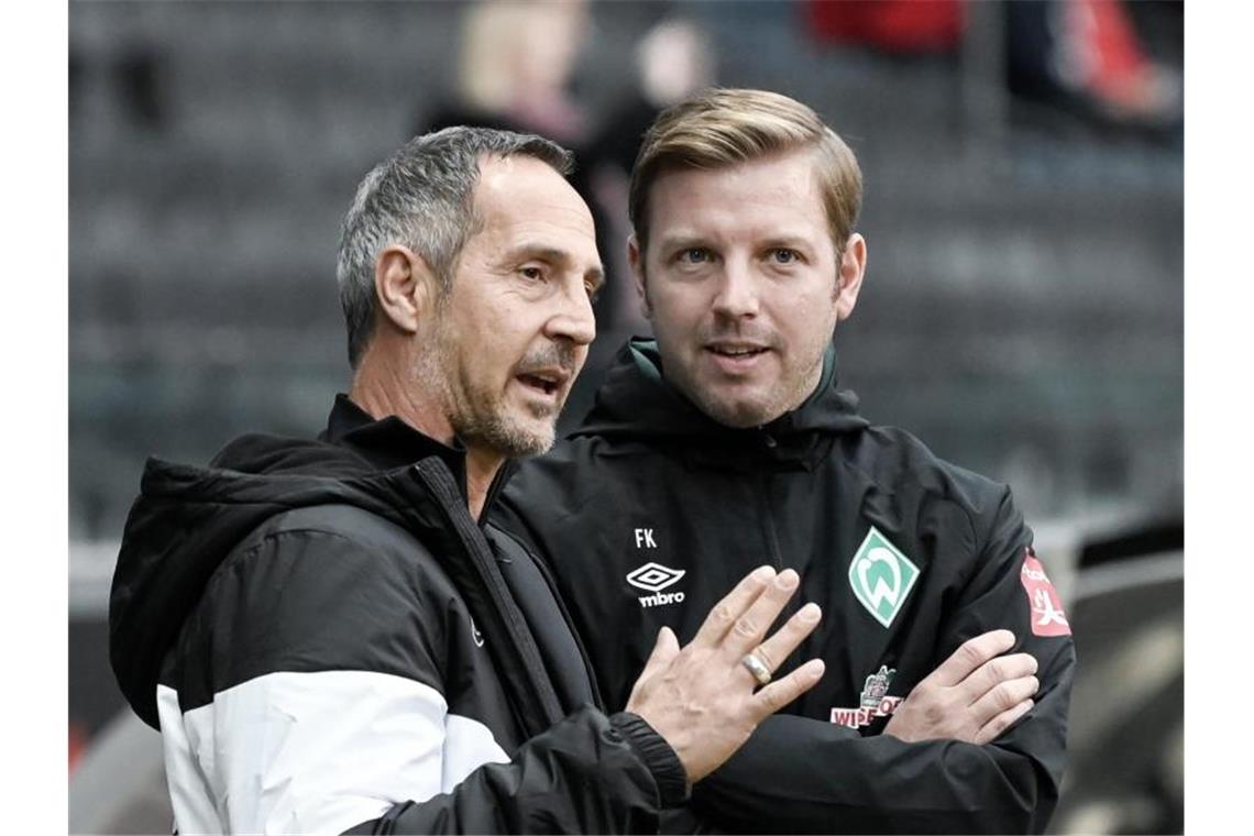 Frankfurts Trainer Adi Hütter (l) und sein Bremer Kollege Florian Kohfeldt (r) unterhalten sich vor Spielbeginn. Foto: Silas Stein/dpa