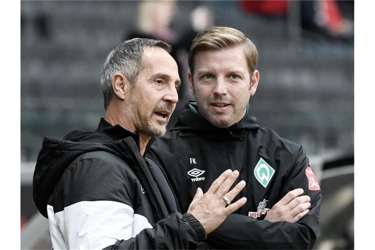 Frankfurts Trainer Adi Hütter (l) und sein Bremer Kollege Florian Kohfeldt (r) unterhalten sich vor Spielbeginn. Foto: Silas Stein/dpa