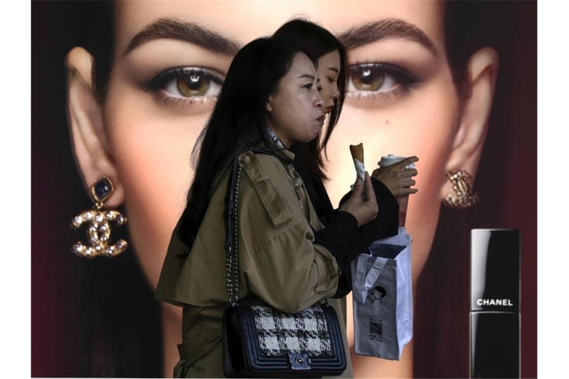 Frauen gehen in einer beliebten Einkaufspassage in Peking an einem Luxus-Kosmetikgeschäft vorbei. Als Zeichen der anhaltenden Erholung nach dem Corona-Einbruch ist Chinas Wirtschaft im dritten Quartal erneut gewachsen. Foto: Andy Wong/AP/dpa