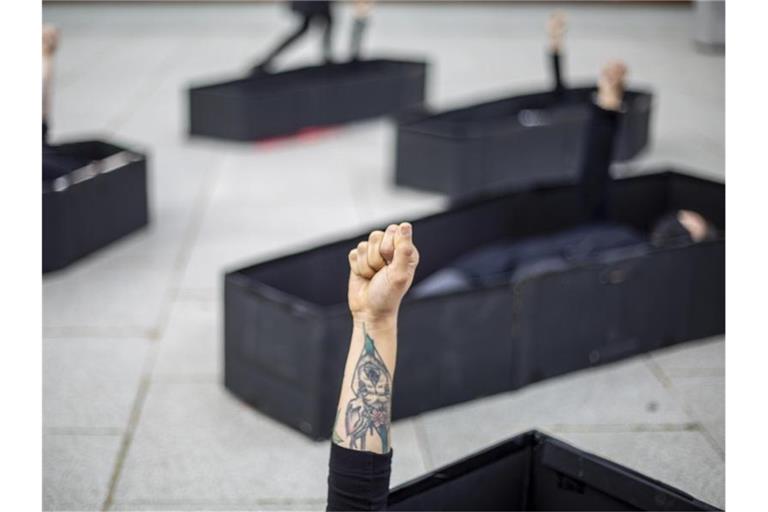 Frauen heben ihre Fäuste, während sie bei einer Demonstration im Vorfeld des Internationalen Frauentages vor dem Bundesgericht von Tel Aviv in Särgen liegen. Die Särge repräsentieren Frauen, die durch häusliche Gewalt getötet wurden. Foto: Ariel Schalit/AP/dpa