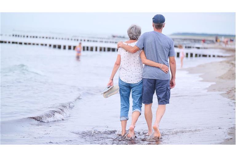 Frauen leben länger: Ein Rentnerehepaar geht an einem  Strand bei Rostock Arm in Arm spazieren