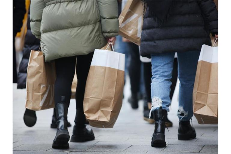 Frauen tragen Einkaufstüten über die Königsallee in Düsseldorf. Foto: Martin Gerten/dpa