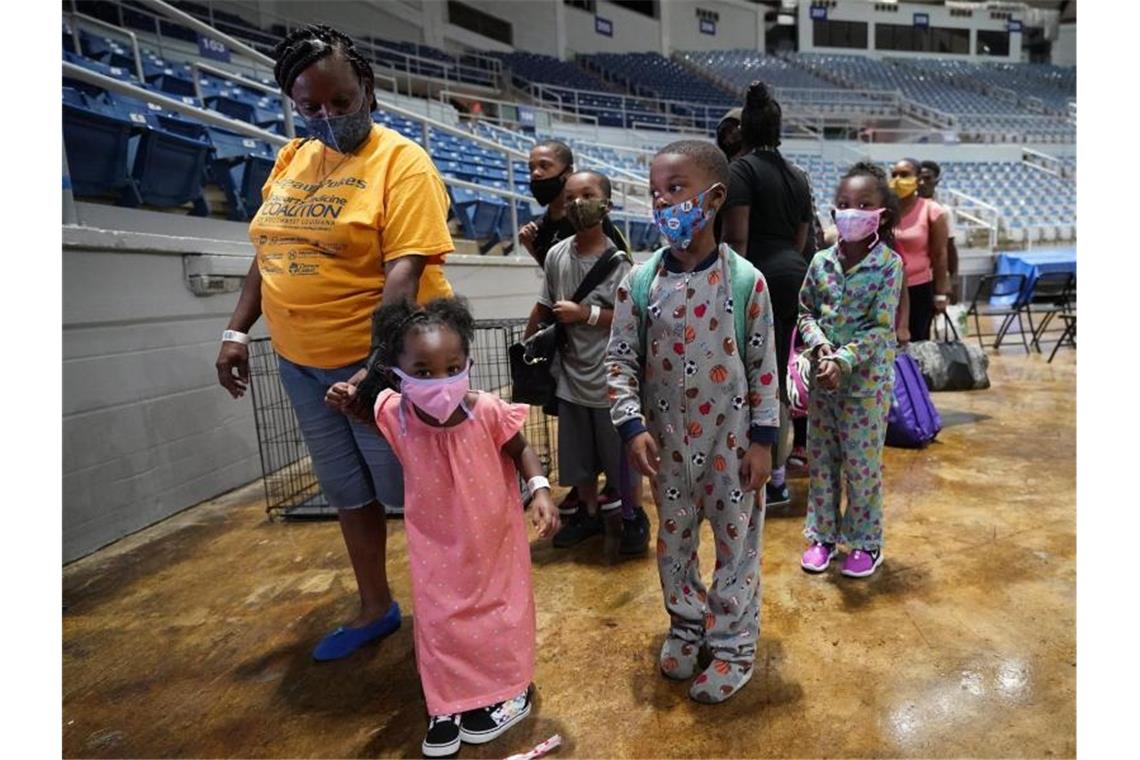 Frauen und Kinder warten in einer Sporthalle in Lake Charles im US-Bundesstaat Louisiana darauf, in eine Notunterkunft gebracht zu werden. Foto: Gerald Herbert/AP/dpa