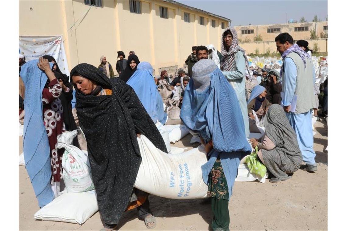 Frauen verlassen eine Verteilungsstelle des Welternährungsprogramm WFP am Stadtrand von Herat mit Lebensmittelrationen. Foto: Marco Di Lauro/WFP/dpa