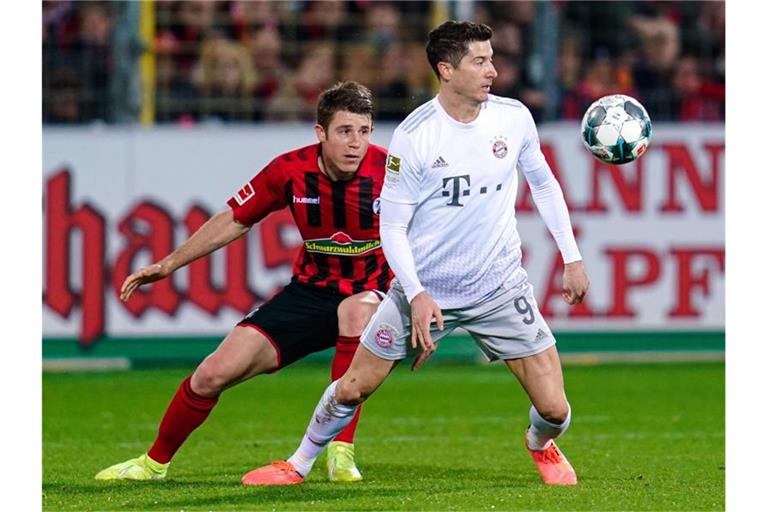 Freiburgs Dominique Heintz (l.) und Münchens Robert Lewandowski kämpfen um den Ball. Foto: Uwe Anspach/dpa