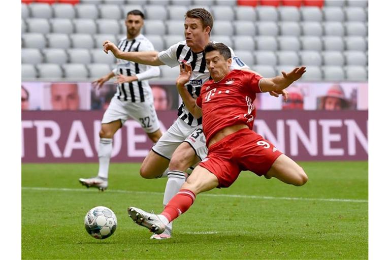 Freiburgs Dominique Heintz (M) und Münchens Robert Lewandowski (r) kämpfen um den Ball. Foto: Sven Hoppe/dpa-Pool/dpa