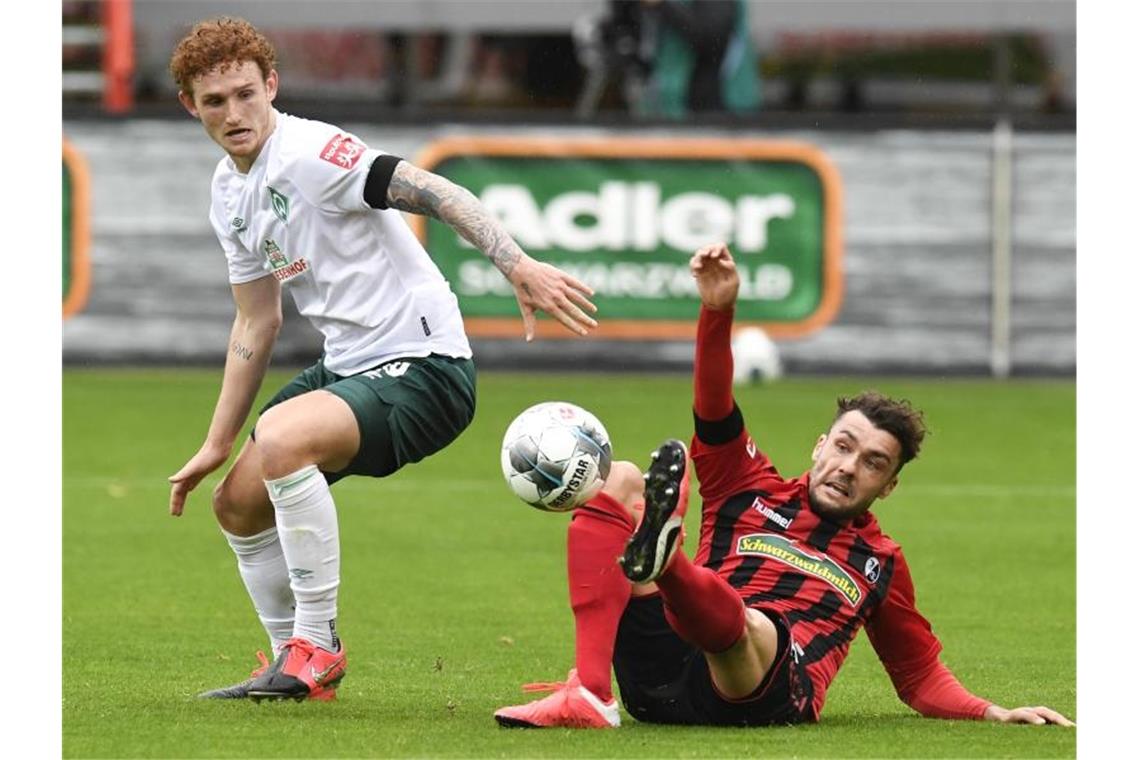 Freiburgs Manuel Gulde (r) kämpft mit Bremens Josh Sargent um den Ball. Foto: Thomas Kienzle/AFP-Pool/dpa