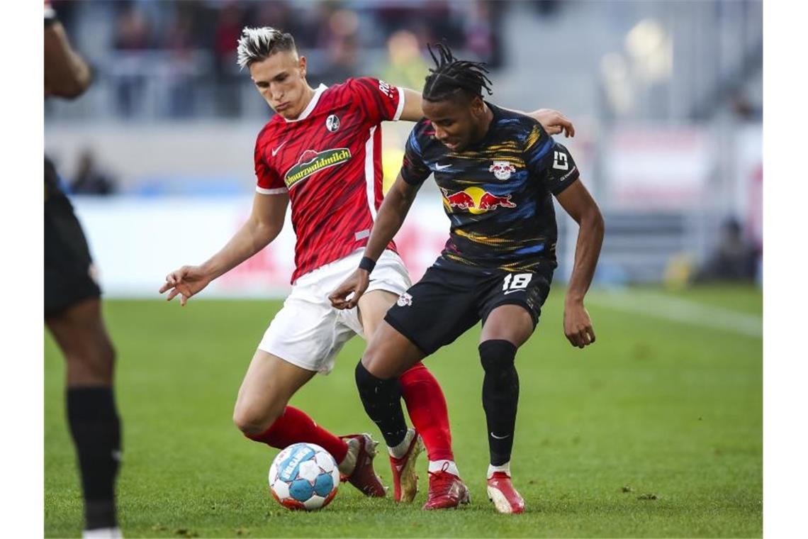 Freiburgs Nico Schlotterbeck (l) versucht Leipzigs Christopher Nkunku (r) vom Ball zu trennen. Foto: Tom Weller/dpa