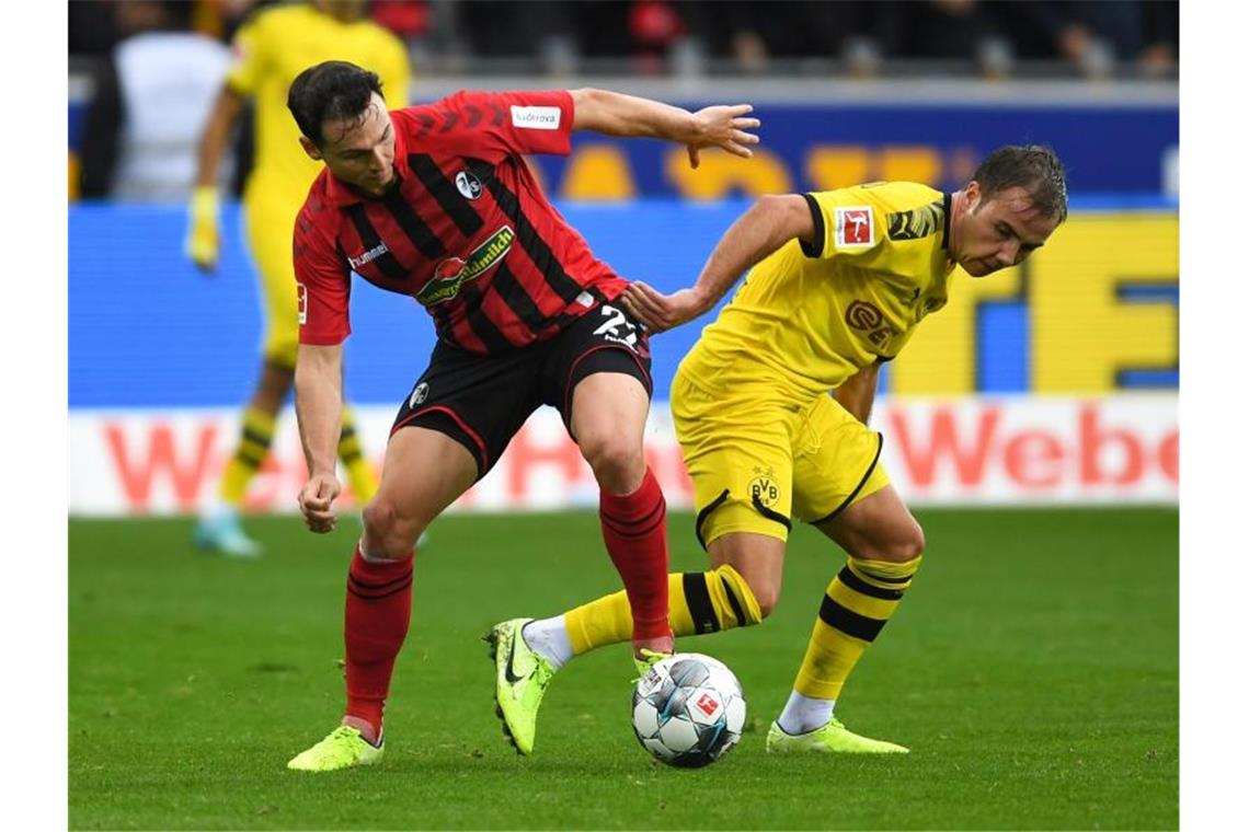 Möglicherweise Gehirnerschütterung bei Höfler Freiburgs Nicolas Höfler (l), hier im Duell mit Mario Götze von Dortmund. Foto: Patrick Seeger/dpa