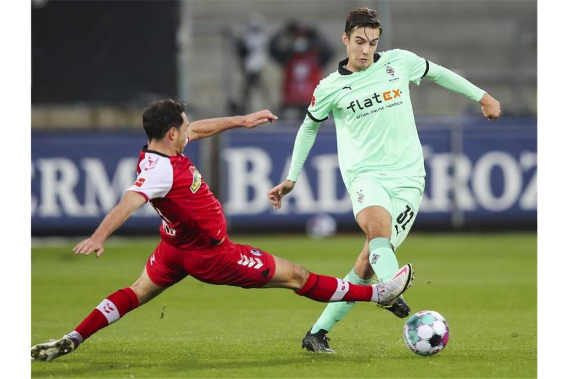 Remis im Gipfel zwischen Bayern und Leipzig - BVB enttäuscht Freiburgs Nicolas Höfler (l) versucht per Grätsche Gladbachs Florian Neuhaus (r) den Ball vom Fuß zu spitzeln. Foto: Tom Weller/dpa