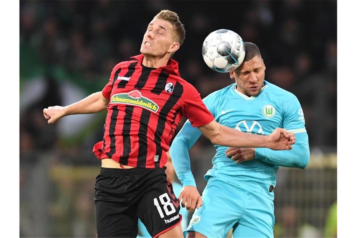 Freiburgs Nils Petersen (l) kämpft mit Wolfsburgs Jeffrey Bruma (r) um den Ball. Foto: Patrick Seeger/dpa