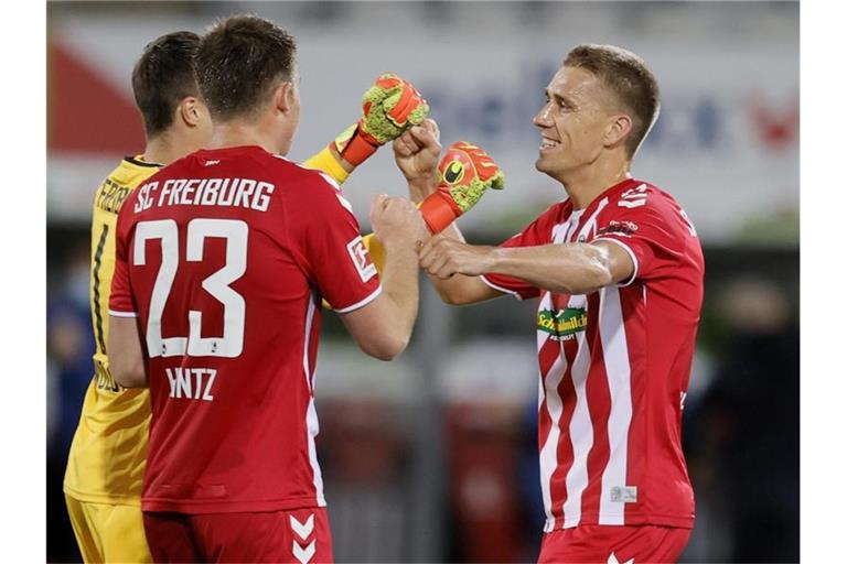 Freiburgs Nils Petersen (r) feiert den Sieg mit Dominique Heintz (M) und Torwart Alexander Schwolow. Foto: Ronald Wittek/epa/Pool/dpa