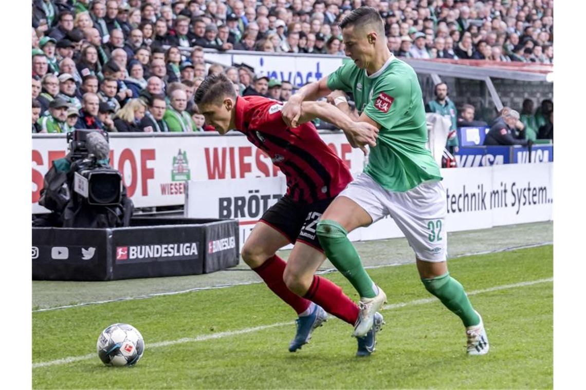 Freiburgs Roland Sallai (l) und Bremens Marco Friedl kämpfen um den Ball. Foto: Axel Heimken/dpa