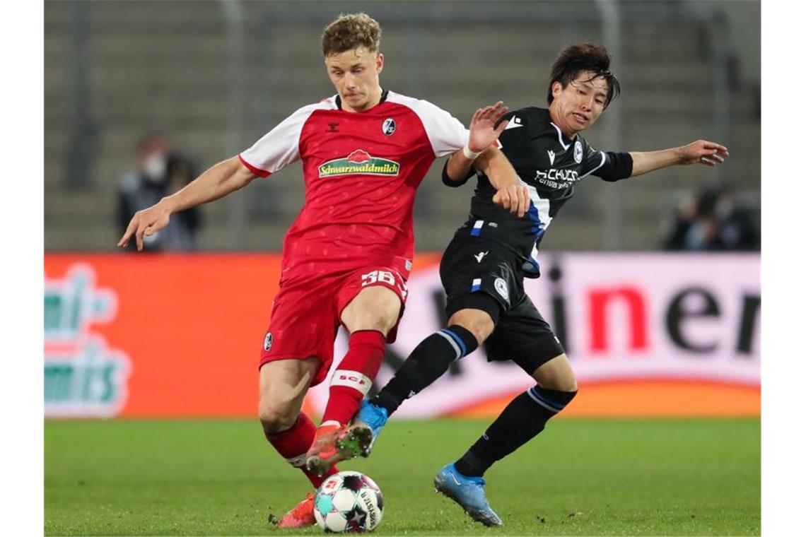 Freiburgs Yannik Keitel (l) und Bielefelds Masaya Okugawa kämpfen um den Ball. Foto: Friso Gentsch/dpa