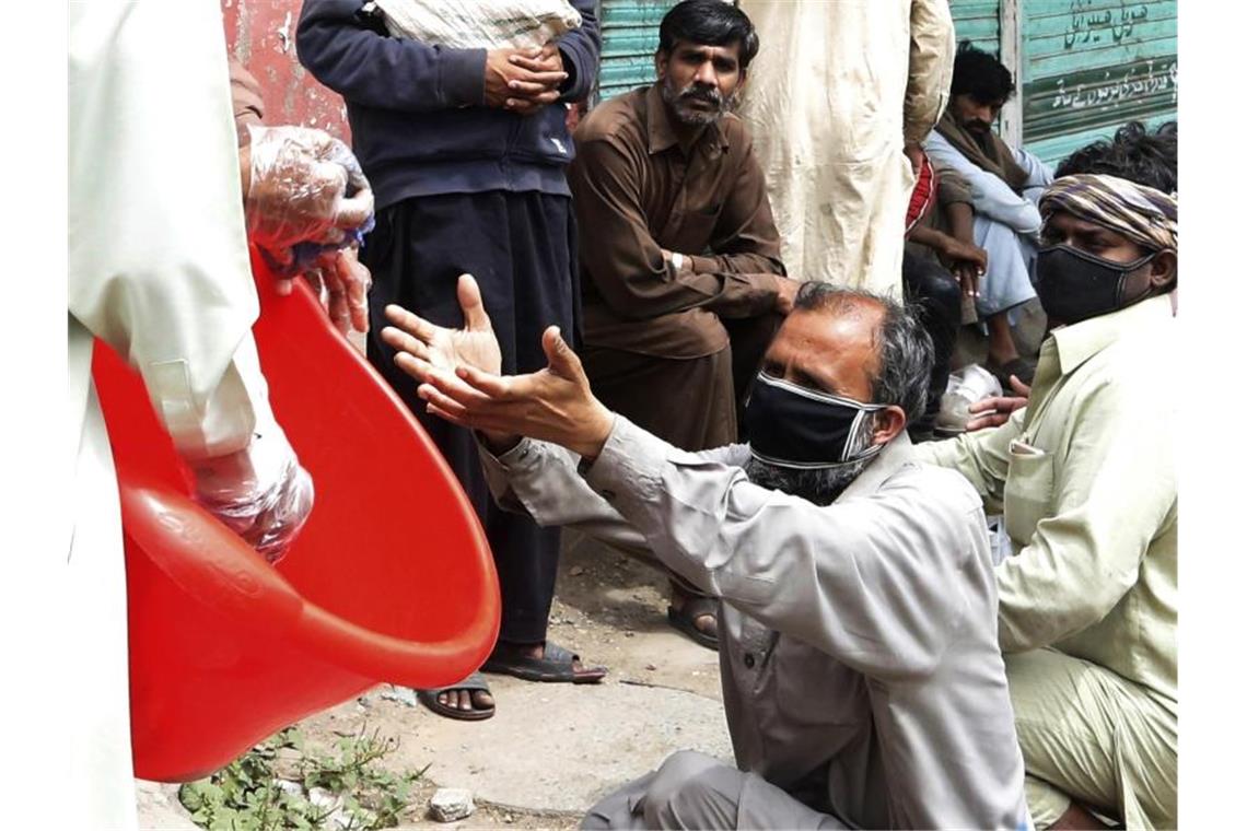 Freiwillige Helfer verteilen Lebensmittel an Tagelöhner im pakistanischen Lahore. Foto: K.M. Chaudary/AP/dpa