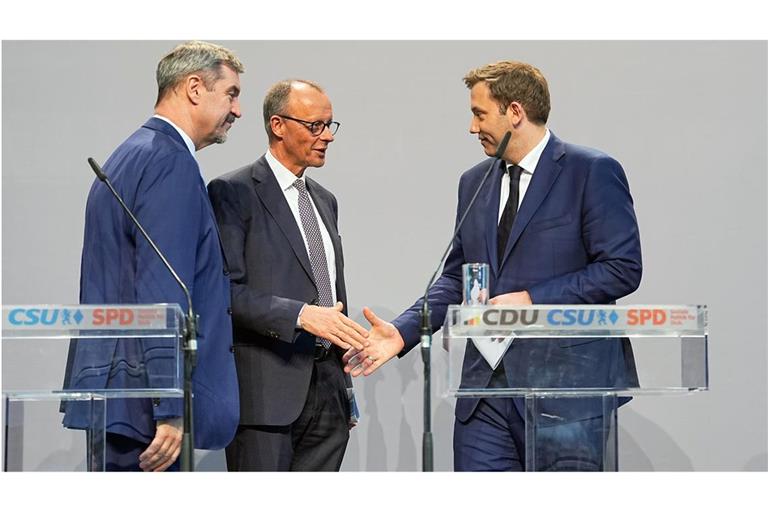 Friedrich Merz (CDU, Mi.) und Lars Klingbeil (SPD, re.), geben sich nach einer Pressekonferenz  zur Vorstellung des Koalitionsvertrages die Hand. Links steht Markus Söder, Ministerpräsident von Bayern und CSU-Vorsitzender.