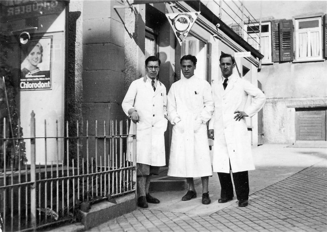 Friseur Gotthilf Kübler und seine Mitarbeiter 1931 vor dem Friseursalon am heutigen Adenauerplatz. Blick von den „Kronen“-Arkaden über die Aspacher Brücke zum Gasthof Stern und der Layer’schen Mühle. Im Zuge des Neubaus der Brücke wurde an die „Krone“ ein Arkadengang angebaut und gegenüber ein Brückenhäuschen mit einer öffentlichen Toilette im Untergeschoss errichtet. Repros: P. Wolf