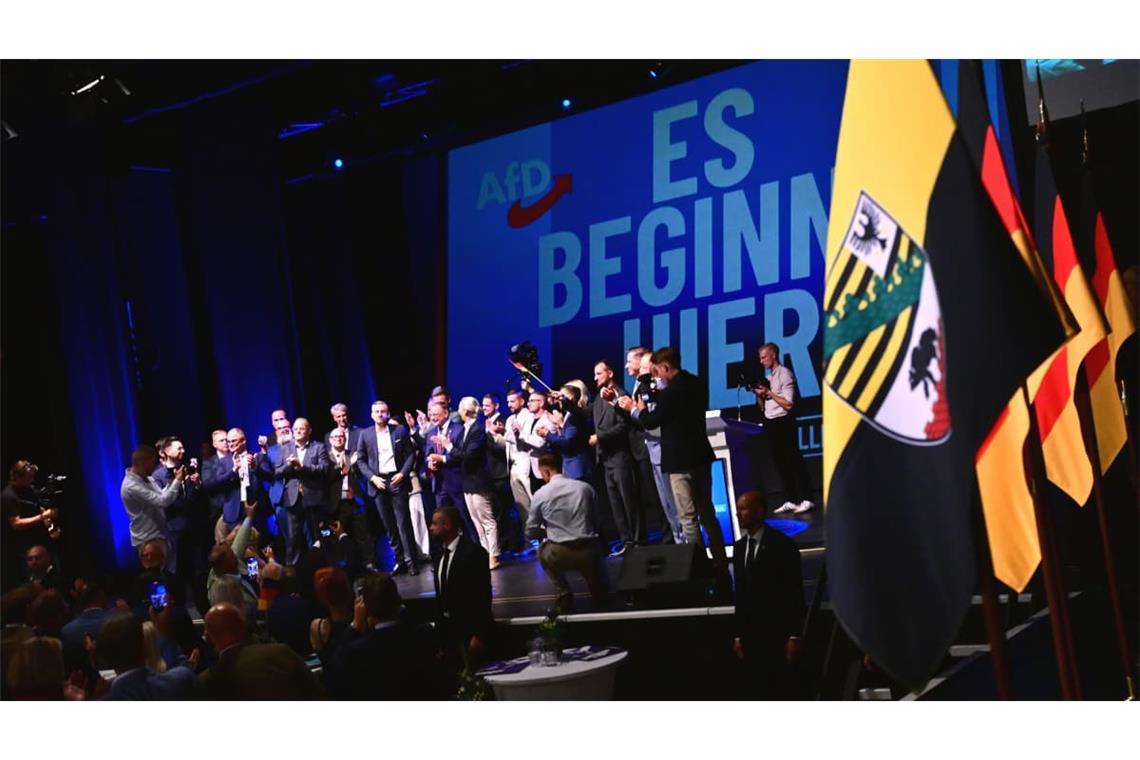 Funktionäre der AfD stehen bei der Wahlparty der AfD im Alten Theater vor dem Schriftzug "Es beginnt hier" auf der Bühne.