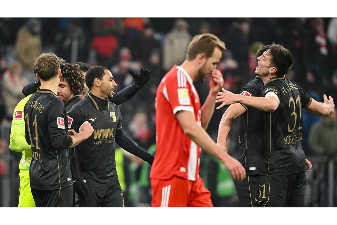 Fußball: Bundesliga, FC Bayern München - FC Augsburg, 19. Spieltag, Allianz Arena. Die Spieler des FC Augsburg jubeln nach Spielende. Davor geht Harry Kane (Bayern München). Das Spiel endete 1:2.