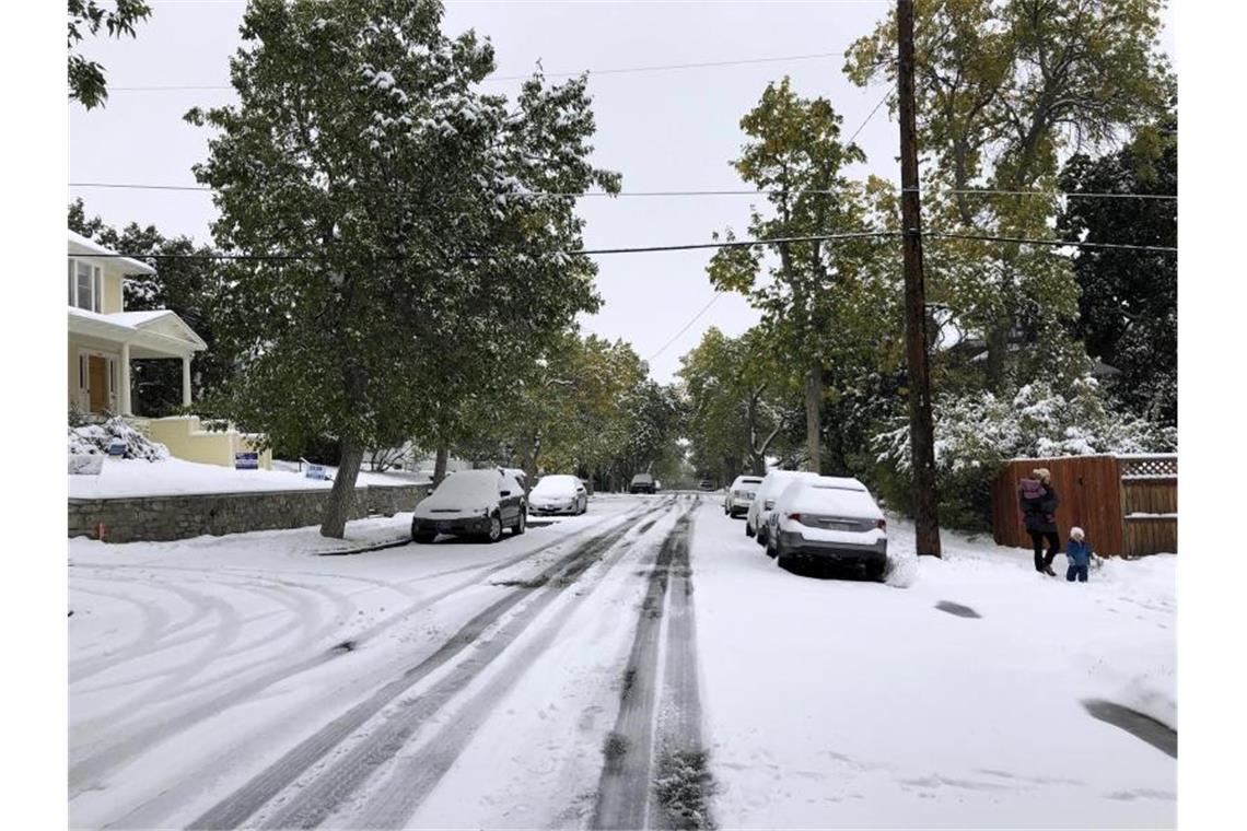 Fußgänger auf einem schneebedeckten Fußweg. Ein Schneesturm hat Teile des US-Bundesstaats Montana lahmgelegt. Foto:  Matt Volz/AP