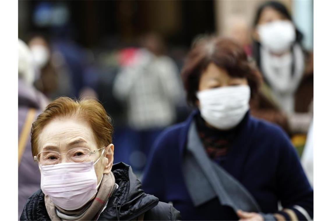 Fußgänger in Tokio tragen Schutzmasken. Mit der gerade laufenden Reisewelle zum chinesischen Neujahrsfest wächst die Gefahr einer Übertragung des Virus. Foto: Eugene Hoshiko/AP/dpa
