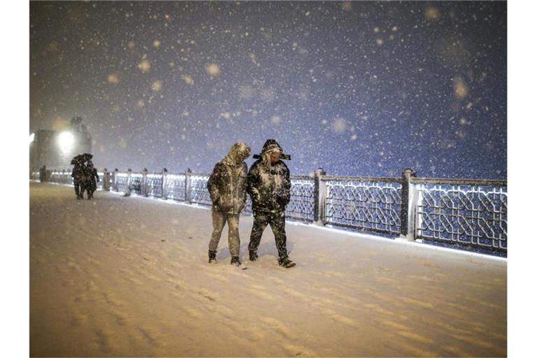 Fußgänger laufen bei Schneefall über die Galata-Brücke in Istanbul. Foto: Emrah Gurel/AP/dpa