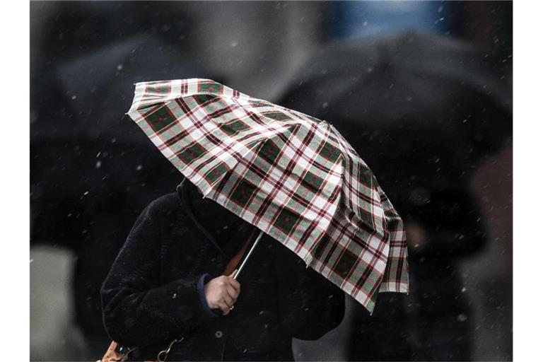 Fußgänger schützen sich mit Regenschirmen gegen den Schneeregen. Foto: picture alliance / dpa/Archivbild