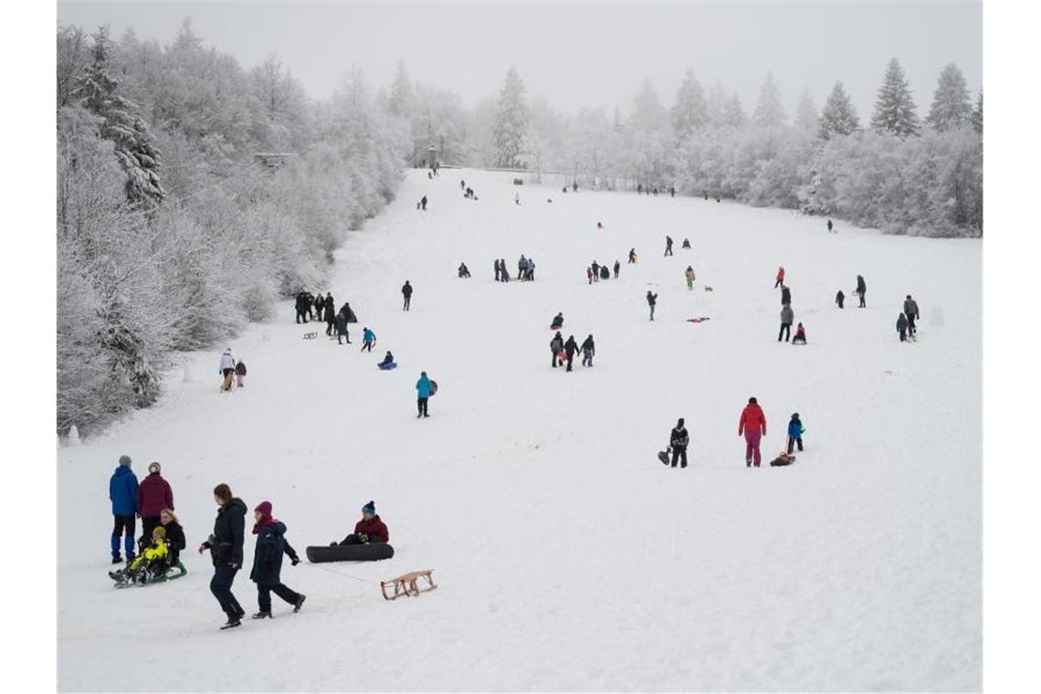 Fußgänger und Schlittenfahrer sind auf einer Piste in Winterberg unterwegs. Foto: Bernd Thissen/dpa