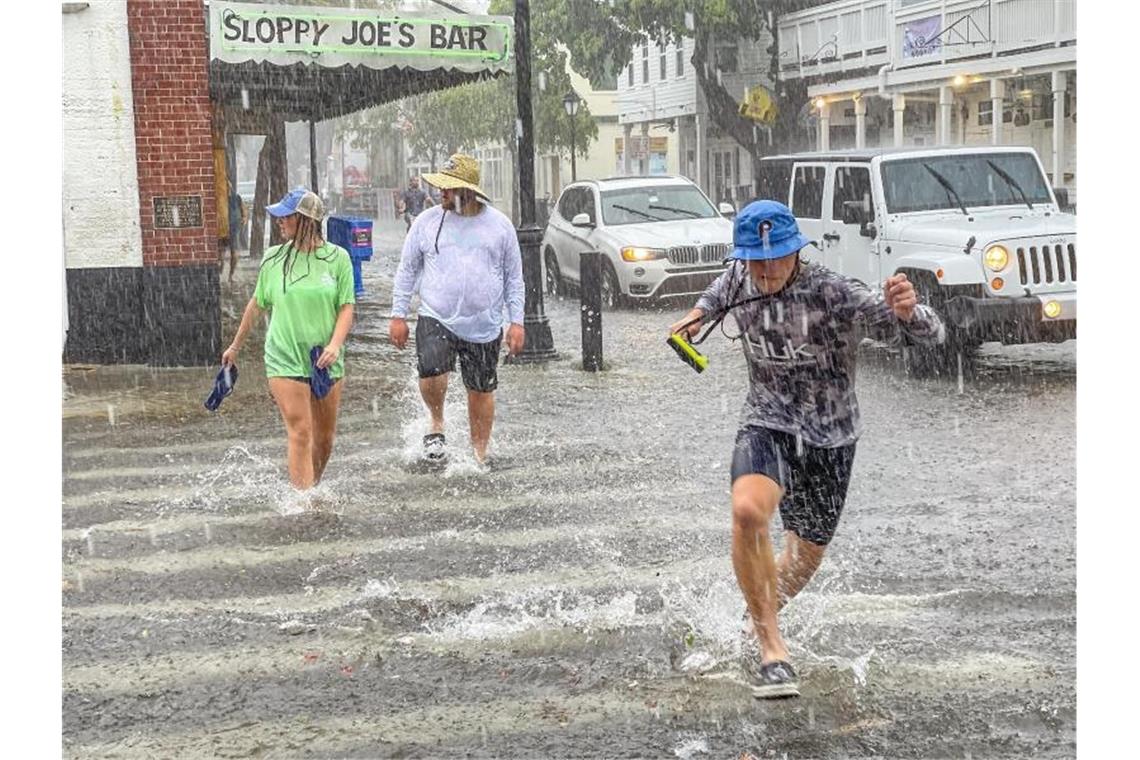 Fußgänger waten in Key West durch Hochwasser an einer Kreuzung. Ausläufer des Tropensturms „Elsa“ mit Sturmböen und Starkregen haben in Florida Straßen überflutet. Foto: Rob O'neal/The Key West Citizen/AP/dpa