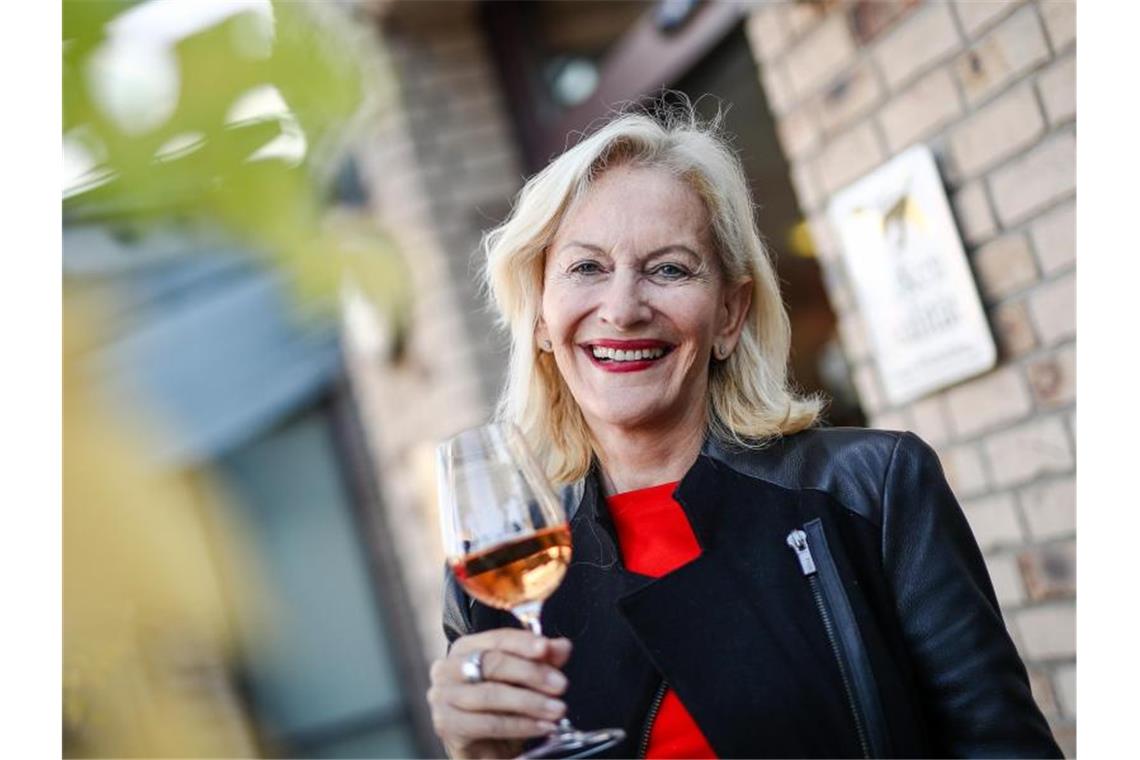 Gaby Hauptmann hält bei der Veranstaltung ein Glas Wein in ihrer Hand. Foto: Christoph Schmidt/dpa