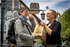 Gaby Siller (rechts) überreicht Sabine Rücker ein bestelltes Vesper als Wegzehrung für die Tour. Fotos: Alexander Becher