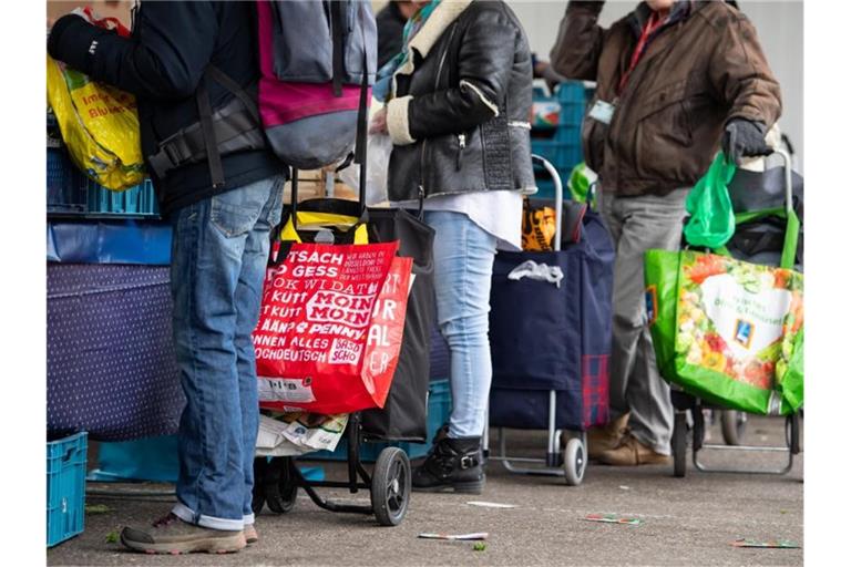 Gäste der Münchner Tafel stehen an der Ausgabestelle am Großmarkt. Foto: Sven Hoppe/dpa