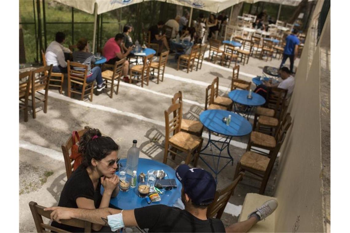 Gäste sitzen in einem Café im Stadtteil Monastiraki im Zentrum Athens. Foto: Socrates Baltagiannis/dpa