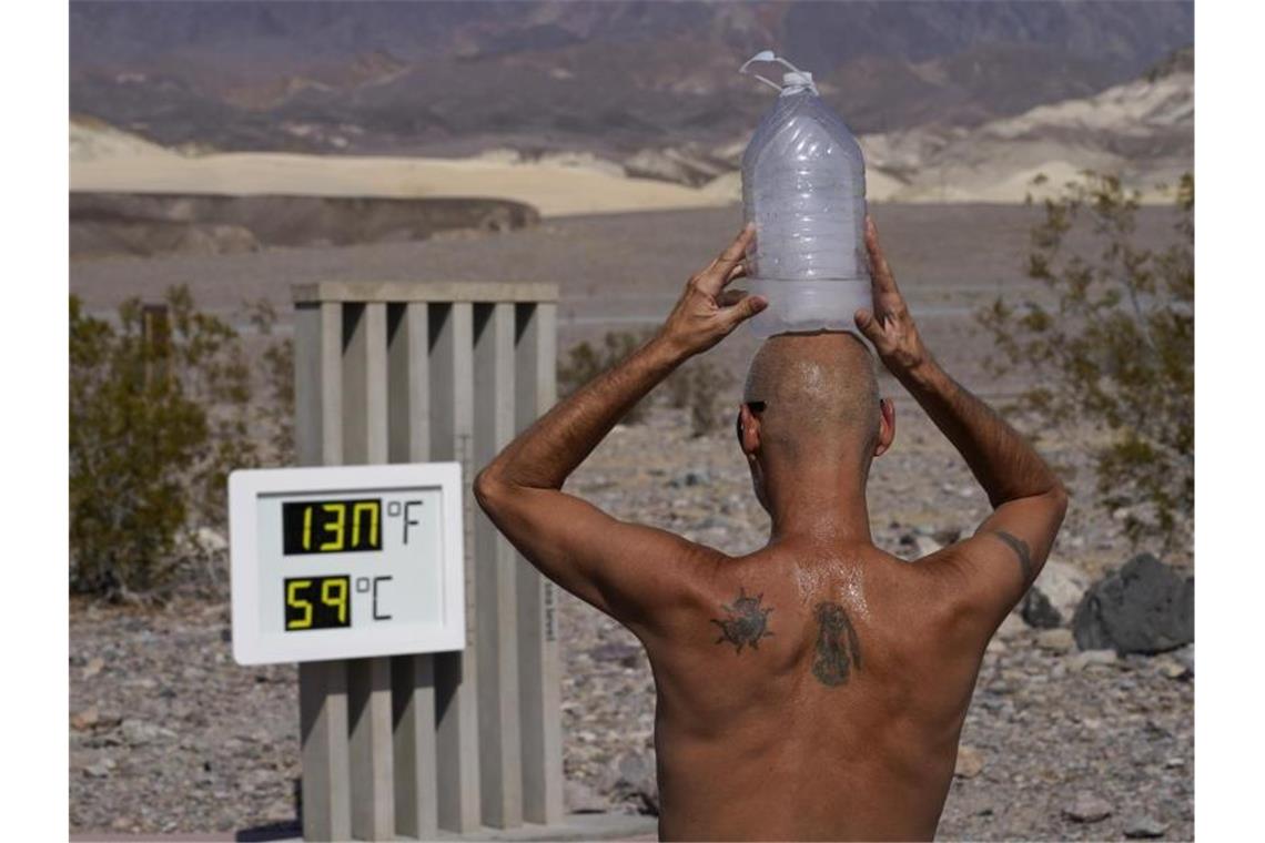 Ganz schön heiß: Ein Mann kühlt sich im „Death Valley“-Nationalpark im US-Bundesstaat Arizona bei 59 Grad Hitze mit einer mit Eiswasser gefüllten Plastikflasche auf dem Kopf ab (Archiv). Foto: John Locher/AP/dpa