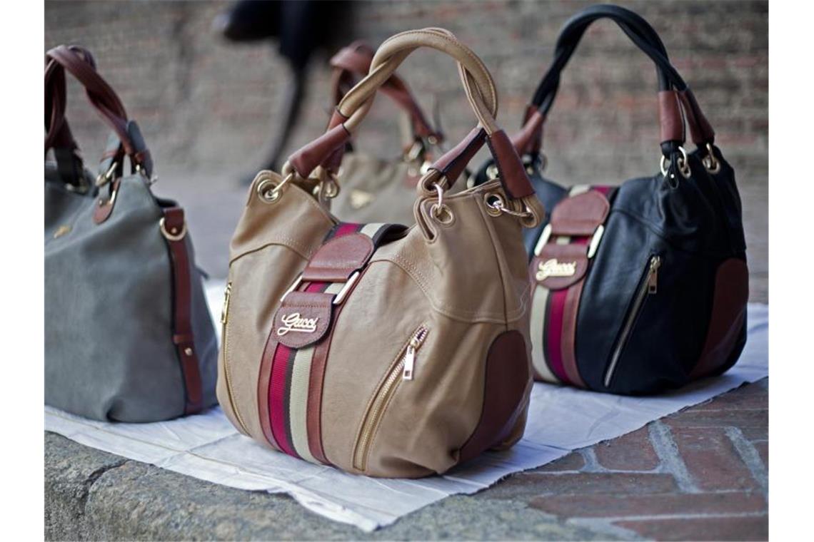 Gefälschte Designer-Taschen werden auf einer Straße in Mailand zum Verkauf angeboten. Foto: picture alliance / dpa