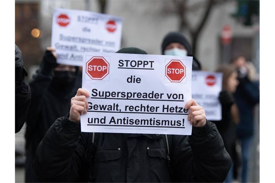 Gegendemonstranten halten am Rande einer Aktion von Gegnern der Corona-Maßnahmen in Frankfurt am Main ein Schild in der Hand. (Archivbild). Foto: Boris Roessler/dpa