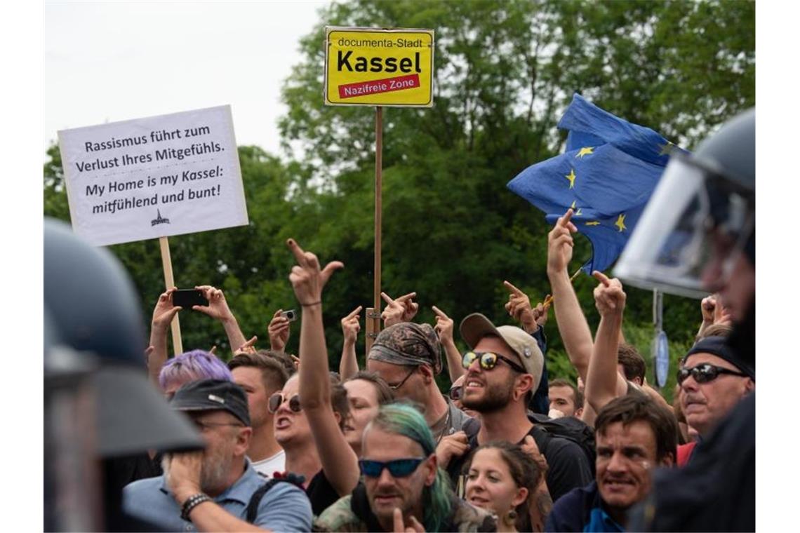Gegendemonstranten stehen in Kassel mit Flaggen und Transparenten den Teilnehmern der rechtsextremen Kundgebung gegenüber. Foto: Swen Pförtner