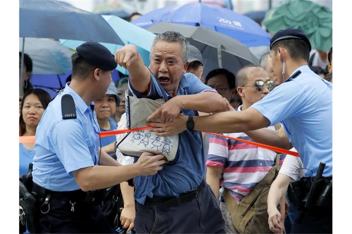 Hongkongs Regierungschefin verurteilt Angriff auf Parlament Gegenprotest: Ein pro-chinesischer Demonstrant wird während einer Kundgebung von Polizisten zurückgehalten. Foto: Kin Cheung/AP
